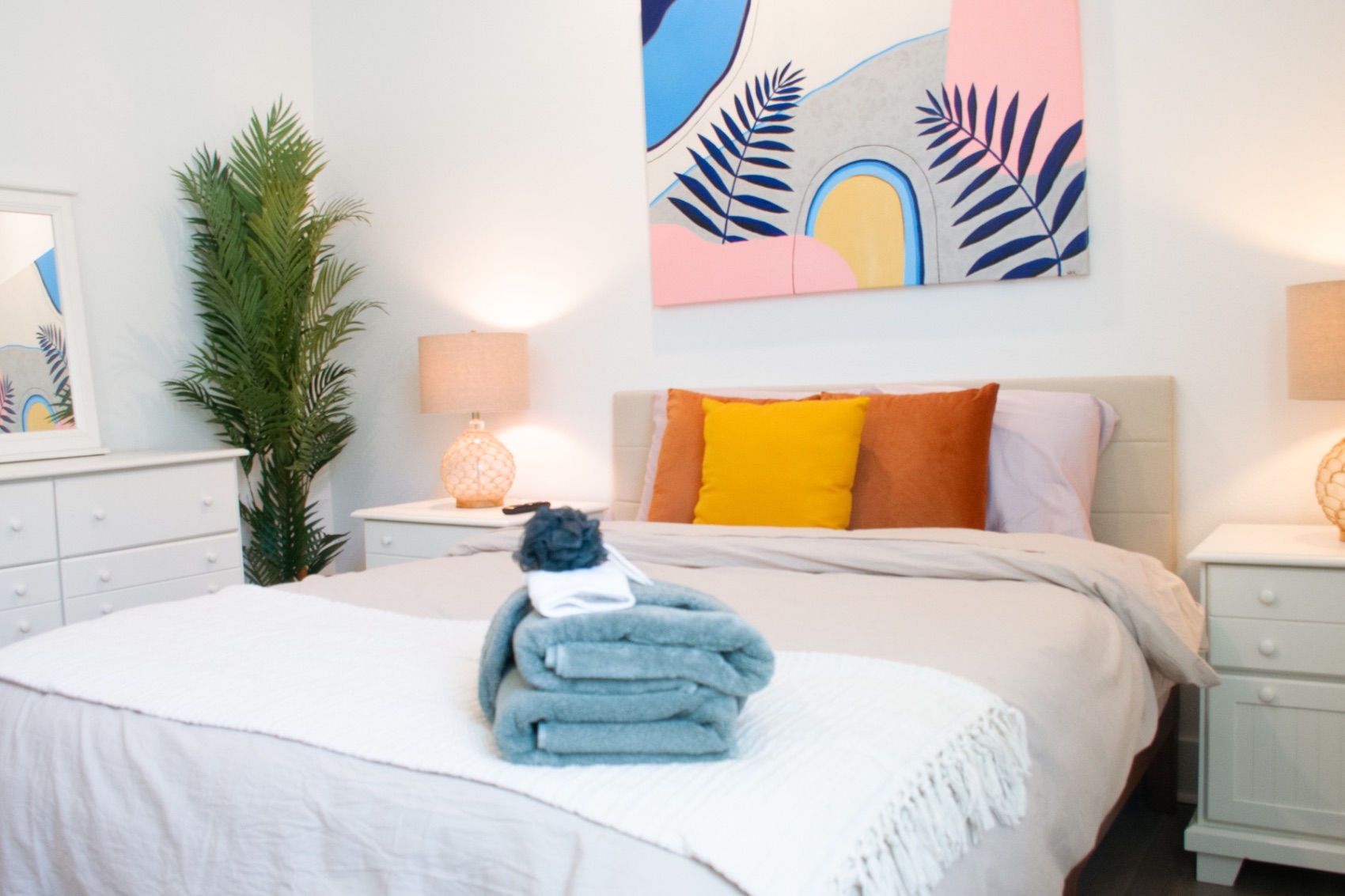 Bedroom with orange and yellow pillows and abstract art